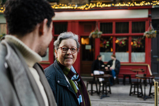 Mature woman smiling interacting with son on city street