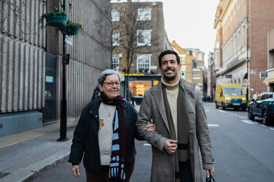 Adult son walking with elderly mother in London