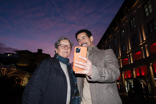 Family taking selfie using smartphone in London at dusk