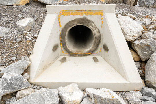 A precast concrete headwall installed at end of a drainage culvert under a road to direct stormwater flow, secure pipe end and prevent erosion