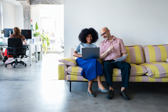 Friendly Office Partners On Sofa With Laptop