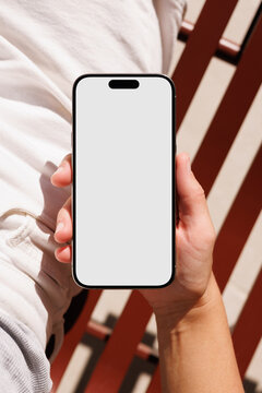 Hand holding smartphone with blank screen outdoors