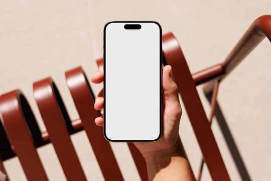 Hand holding smartphone with blank screen outdoors mockup