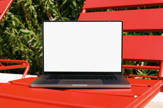 Laptop mockup with white screen on red outdoor chair