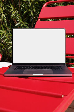 Laptop mockup with white screen on red outdoor chair