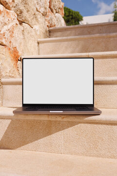 Laptop with white screen on outdoor stone steps summer mockup