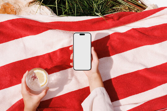 Phone with blank screen on red striped towel travel mockup