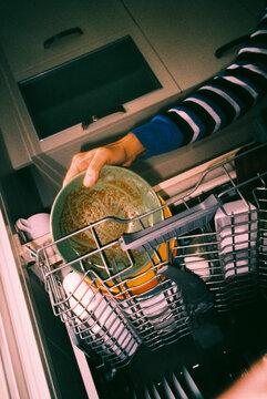 a man loading dirty plates into a dishwasher, 35mm film
