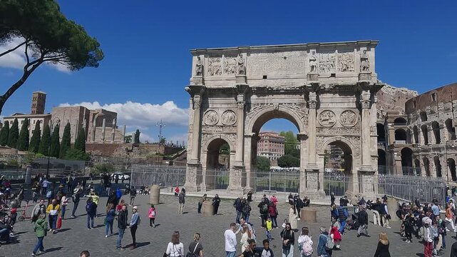 Aerial drone shot of Arch of Constantine And The Colosseum with tourists viewed from via di S. Gregorio on sunny day, slow motion
