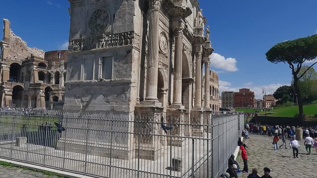 Aerial drone shot of Arch of Constantine And The Colosseum with tourists viewed from via di S. Gregorio on sunny day, slow motion