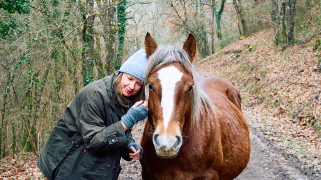 Blonde woman hugging a pregnant mare