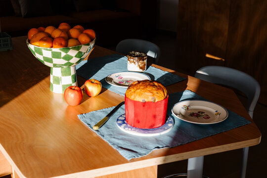 Dining table in an apartment showing a fruit bowl, a small cake