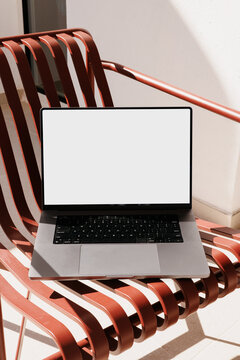 Summer laptop mockup with white screen on red chair outdoors