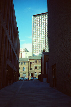 View down a shadowed street to old and new buildings, Sheffield UK