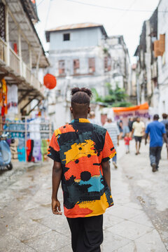 Young man walking through vibrant Stone Town alley