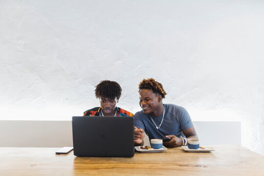 Young African friends sharing laptop in Stone Town cafe