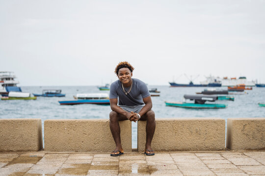 Young man smiling sitting on Stone Town Zanzibar waterfront