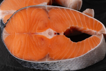 Fresh salmon fillet cut showing orange flesh on a black background ready for cooking in the kitchen