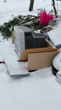 Old CRT Television Abandoned On Snow, Covered Pallet And Cardboard Amid Roadside Debris, Frost tipped Screen, Weathered Plastic And Rusted Metal, Bleak Winter Landscape, Melancholic Solitude.