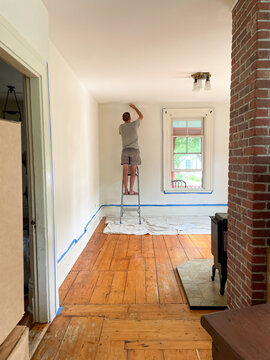 Man painting walls in an empty home with moving boxes