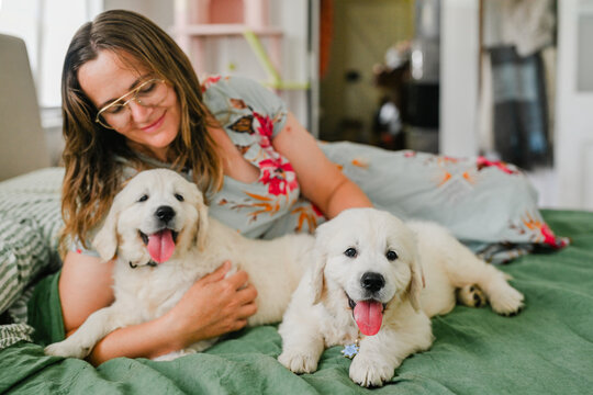 Woman laying in bed with 2 puppies 