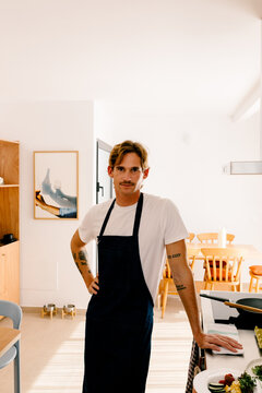 Modern man looking at the camera, posing in an apron