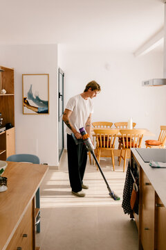 A modern young man tidying up during a quiet morning indoors