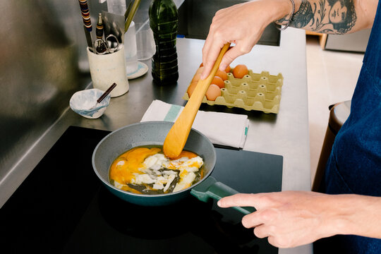 Detail of unknown man using an induction stove to prepare healthy meal