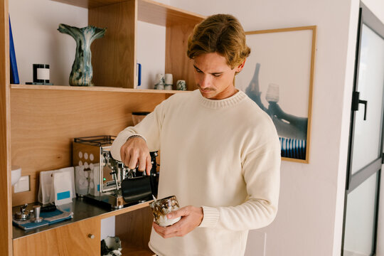 Young man enjoying a latte in a modern contemporary apartment