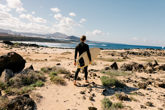Full-body portrait of surfer looking to the horizon in panoramic shot