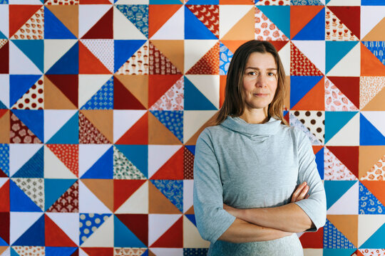 Creative Woman Stands Proudly in Front of Colorful Quilt Backdrop