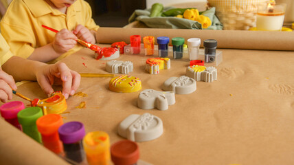 Creative kids painting colorful decorations with bright paints on paper