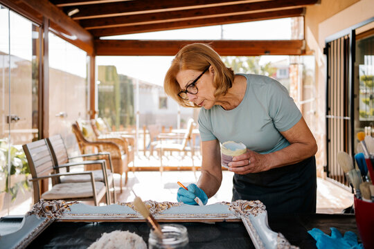 Senior woman restoring vintage picture frame