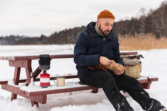 Hiker taking a break on a picnic bench in a snowy winter landscape