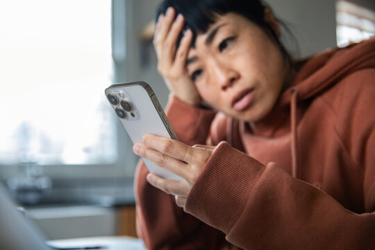 Worried woman reading smartphone message at home