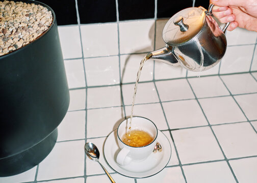 Tea is Poured From a Silver Teapot Into a White Teacup