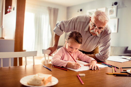 Grandfather helping granddaughter with homework at home