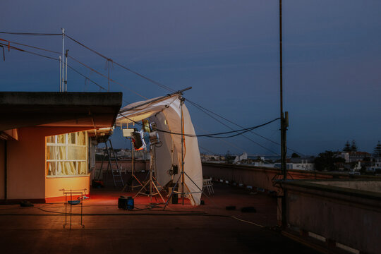 Rooftop film set with lighting equipment at dusk