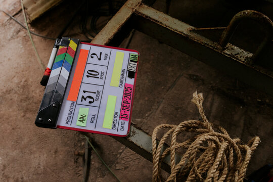 Film clapperboard on rusty surface with rope nearby