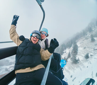Two People Riding Ski Lift on Foggy Winter Day