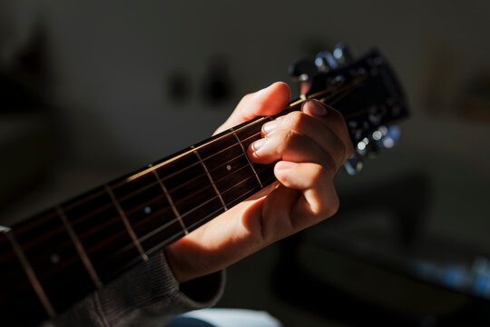 Hand playing acoustic guitar strings