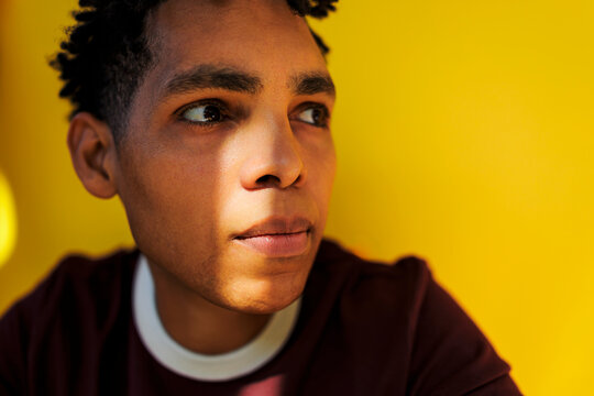 Man contemplating against yellow background with strong light
