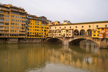 Obraz premium Florence features buildings beside the Arno River with the Ponte Vecchio bridge connecting both sides