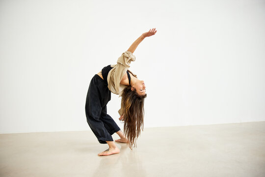 Woman performs dance pose in studio with minimal background