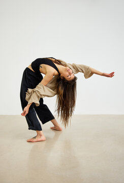 Woman dancing in studio with natural lighting and simple backdro