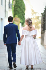 Naklejka premium Newlywed couple walking hand in hand on a street