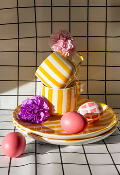 Colorful still life with striped cups, flowers and painted eggs