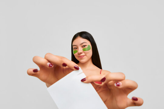 Woman showing skincare patch packaging with smile