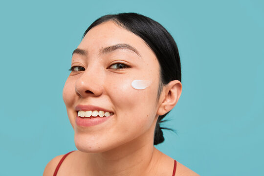 Smiling woman with face cream on cheek