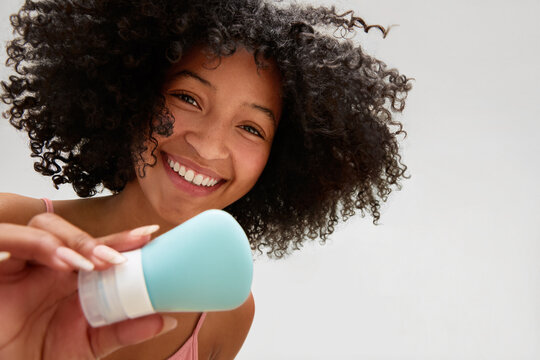 Smiling woman holding skincare bottle 